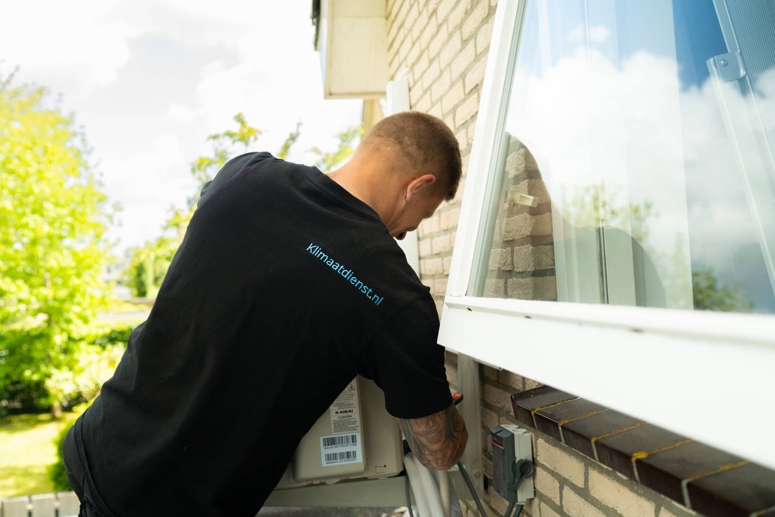 Installateur die een buitenunit van een airco aan het plaatsen is